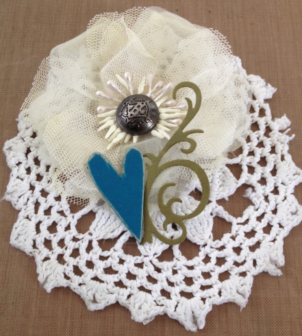 Crocheted doily, chipboard, fabric flower, metal button & paper swirl